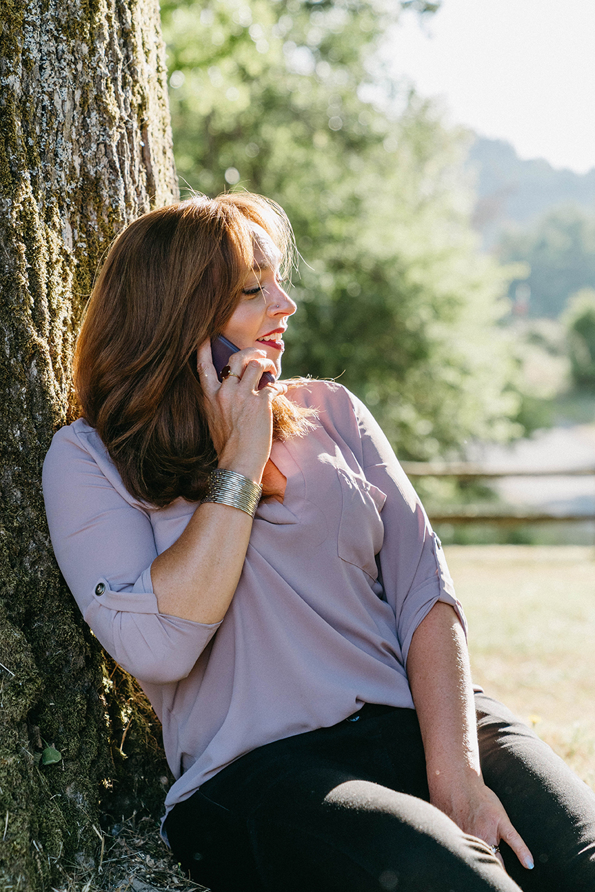 Elizabeth Miner takes a call while sitting beneath a tree.