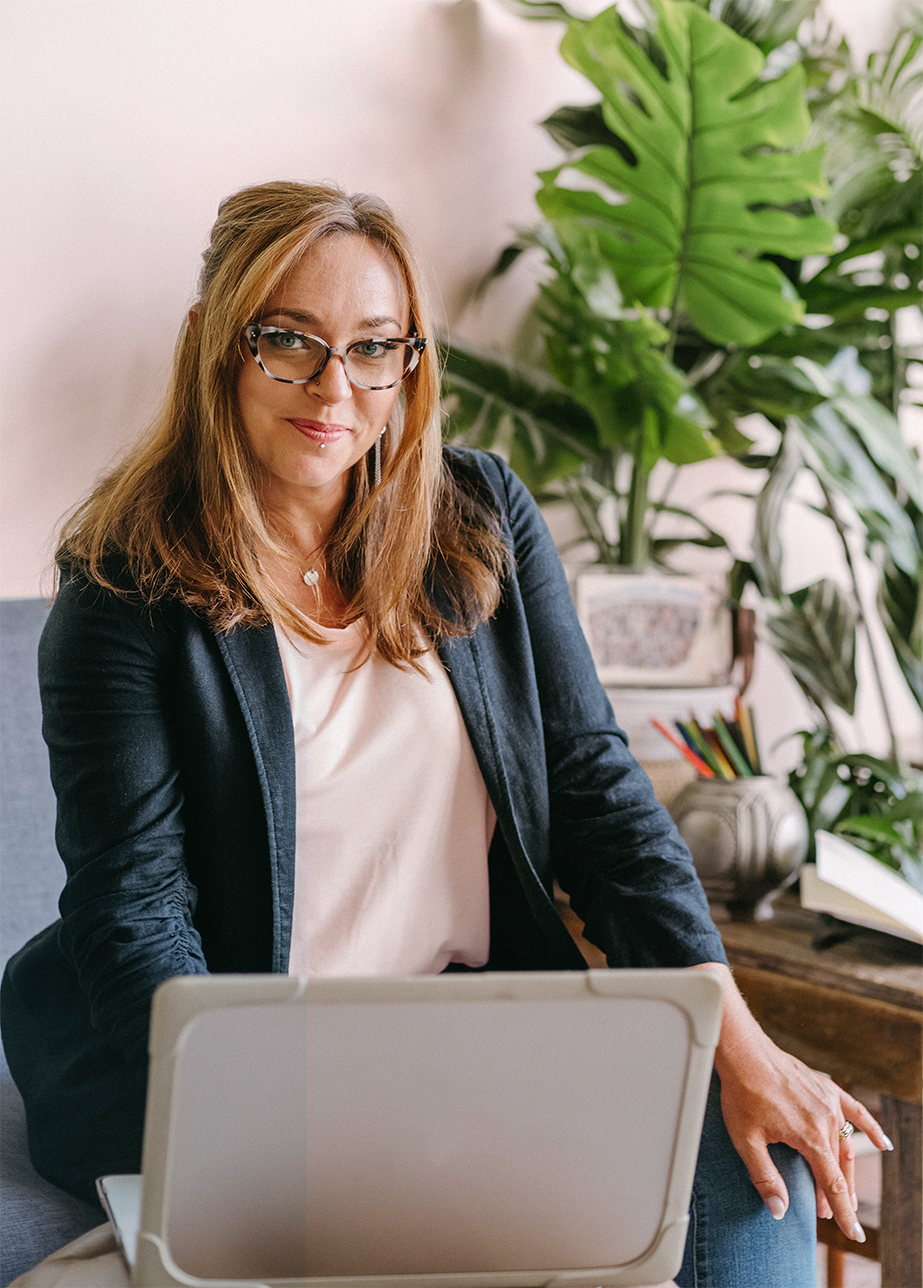 Elizabeth Miner smiles from behind a laptop.
